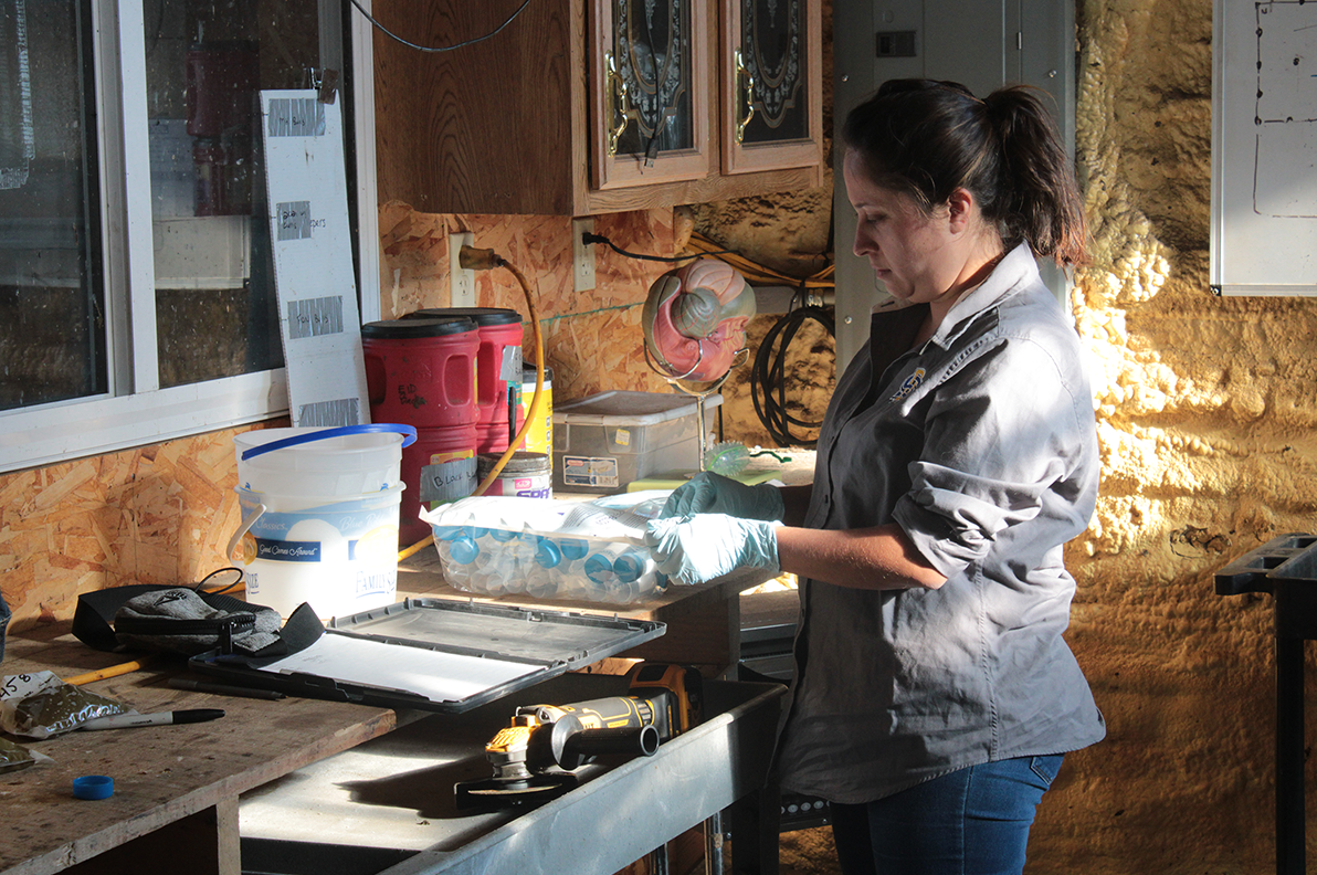 Anlly Fresno Rueda stands over a busy work table while preparing test tubes. 